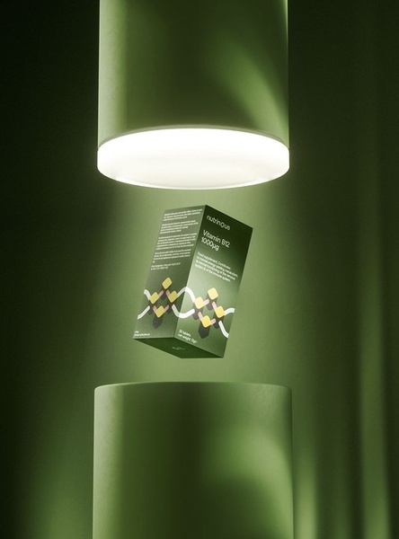 This creative showcases a Vitamin B12 supplement box suspended in a studio-lit environment, emphasizing premium quality through clean composition and monochromatic tones.